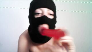 Masked teen giving a blowjob to a dildo