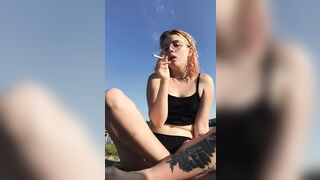 A blonde girl smokes a cigarette on the beach. Do you want her to start masturbating right there?